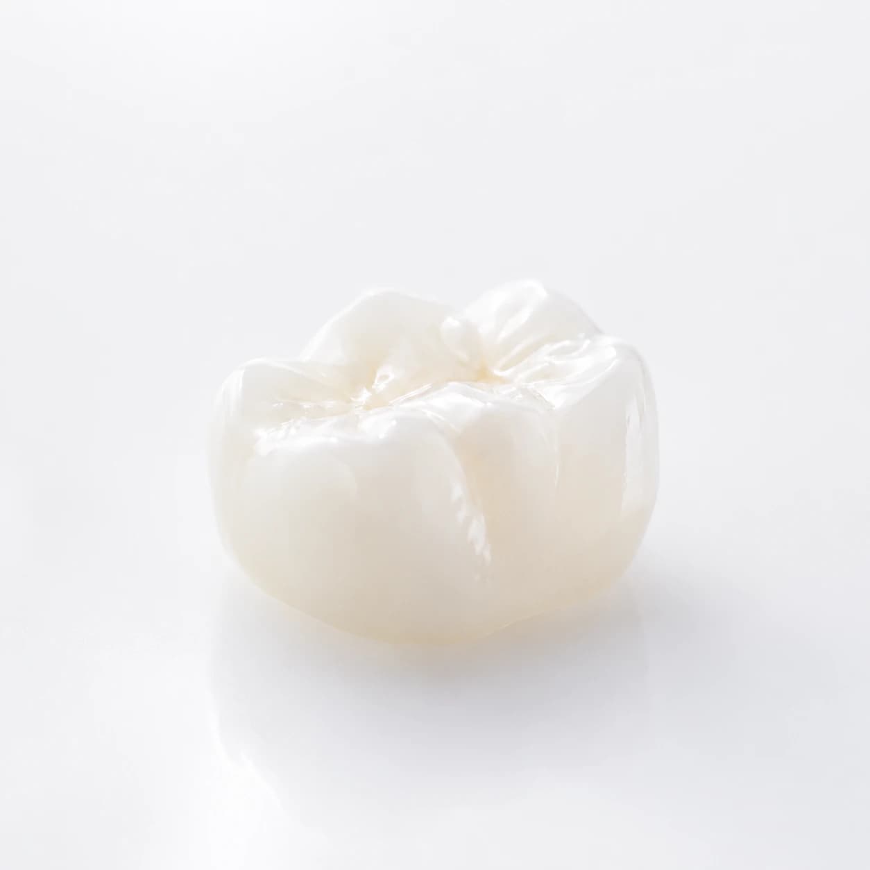 White ceramic dental crown photographed as a premium product close-up